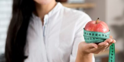 close-up-woman-s-hand-holding-red-apple-with-green-measurement-tape