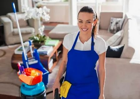 Two women diligently cleaning a room, with sunlight streaming through a nearby window.